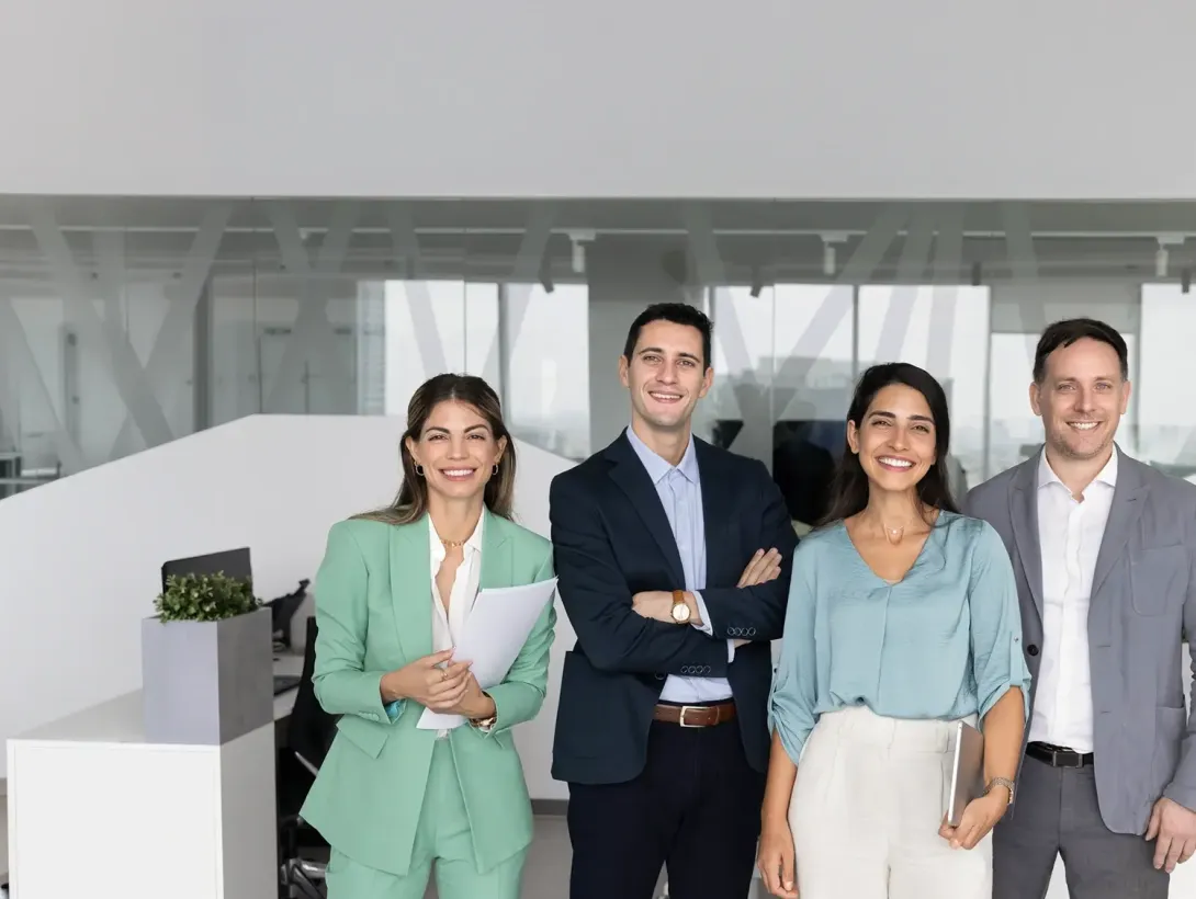 Four business professionals standing together in a bright, modern office space.