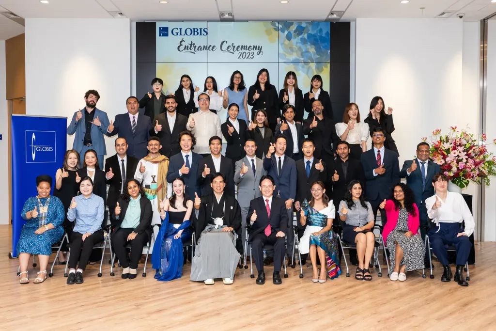 Aiman Alkebsi (second row) with fellow GLOBIS Full-time MBA students at the 2023 Entrance Ceremony, giving a thumbs-up.
